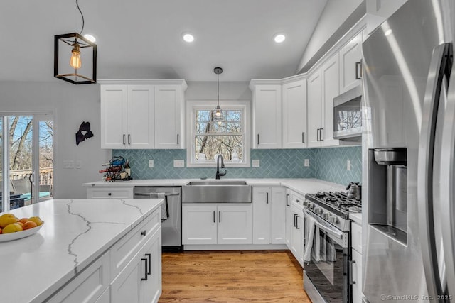 kitchen featuring a wealth of natural light, white cabinets, stainless steel appliances, and a sink