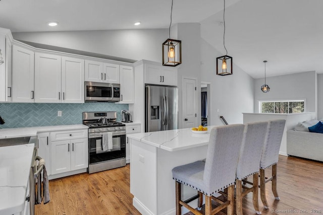 kitchen with stainless steel appliances, a breakfast bar, light wood-style flooring, and white cabinets