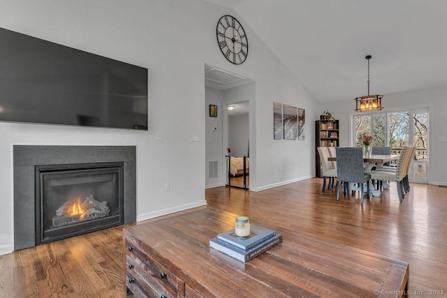 dining room featuring a glass covered fireplace, wood finished floors, visible vents, and baseboards