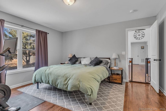 bedroom with visible vents, baseboards, and wood finished floors