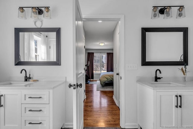 bathroom with a sink, two vanities, and wood finished floors