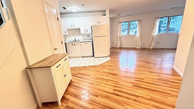 kitchen with butcher block countertops, white appliances, a sink, white cabinetry, and light wood-type flooring