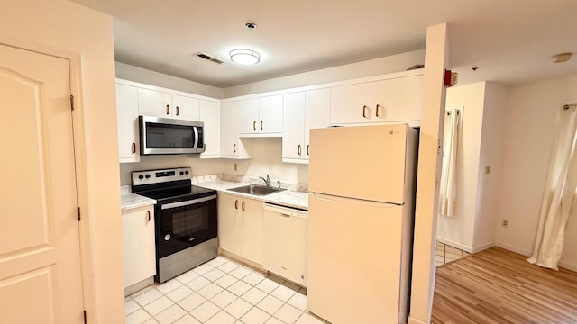 kitchen with a sink, visible vents, white cabinets, light countertops, and appliances with stainless steel finishes