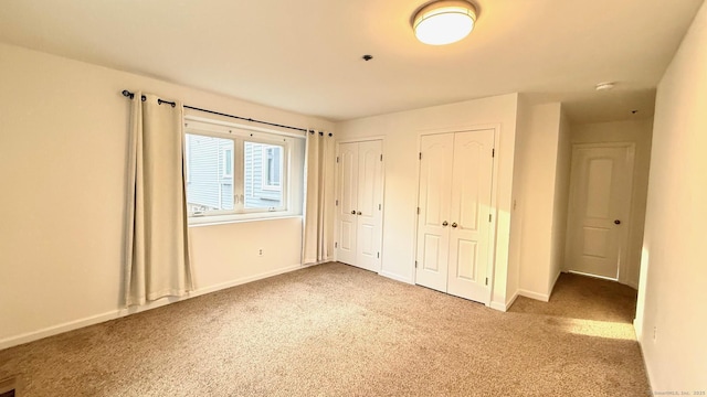 unfurnished bedroom with carpet, baseboards, and multiple closets