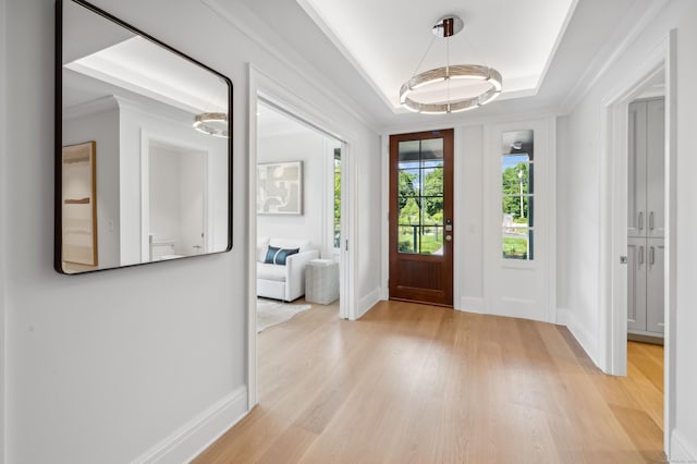 entryway with light wood-style floors, baseboards, and a tray ceiling