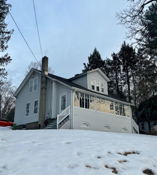 view of front facade featuring a chimney and a sunroom