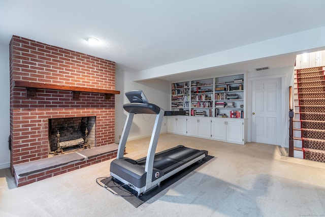 workout area with visible vents, a fireplace, light colored carpet, and baseboards