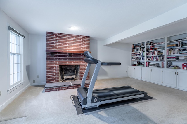 exercise area featuring a brick fireplace, baseboards, and carpet floors