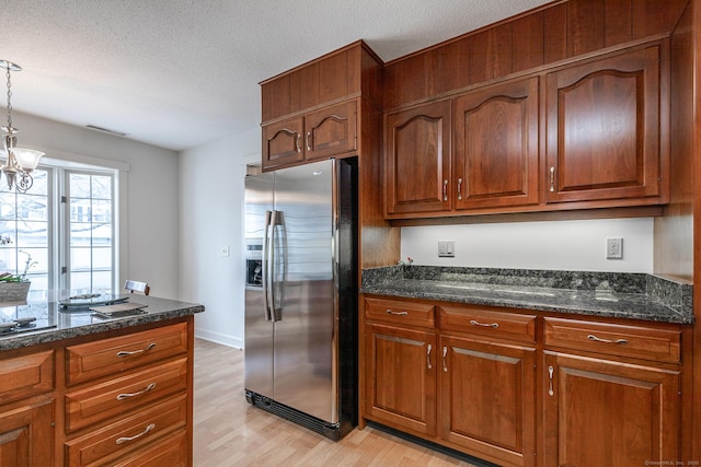 kitchen featuring stainless steel fridge with ice dispenser, pendant lighting, light wood-style floors, brown cabinetry, and a textured ceiling