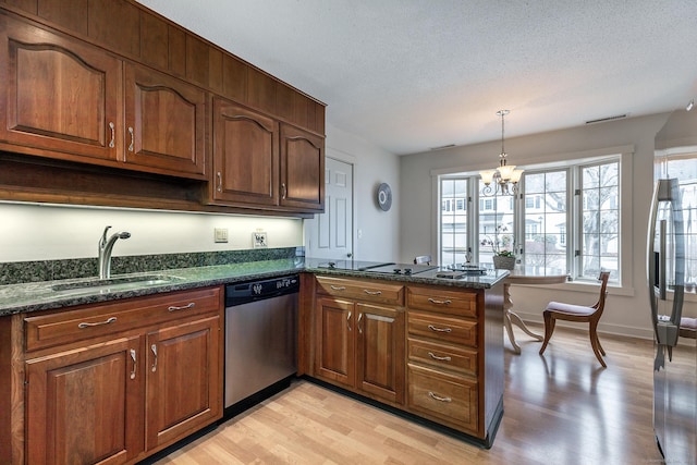 kitchen featuring light wood finished floors, a peninsula, a sink, a textured ceiling, and stainless steel dishwasher