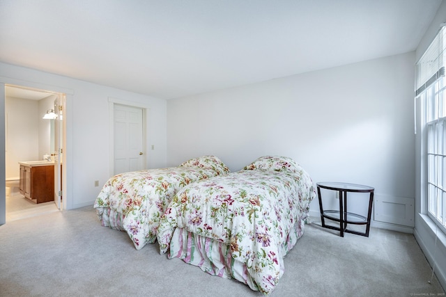 bedroom featuring carpet flooring, multiple windows, ensuite bathroom, and a sink