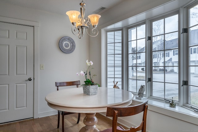 dining space with a wealth of natural light, visible vents, dark wood-type flooring, and a notable chandelier