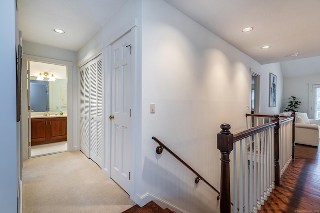 corridor featuring a sink, carpet flooring, an upstairs landing, and recessed lighting