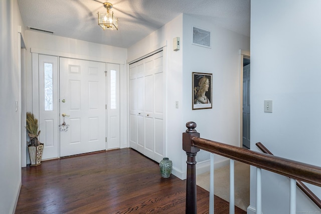 entrance foyer with visible vents, a textured ceiling, and dark wood-style flooring