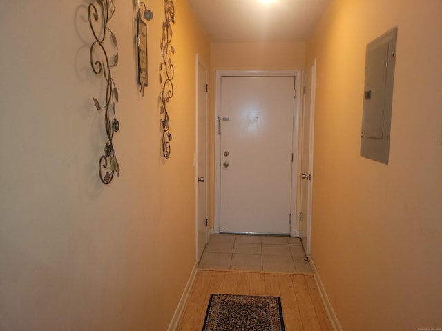 hallway with light wood-style flooring, electric panel, and baseboards