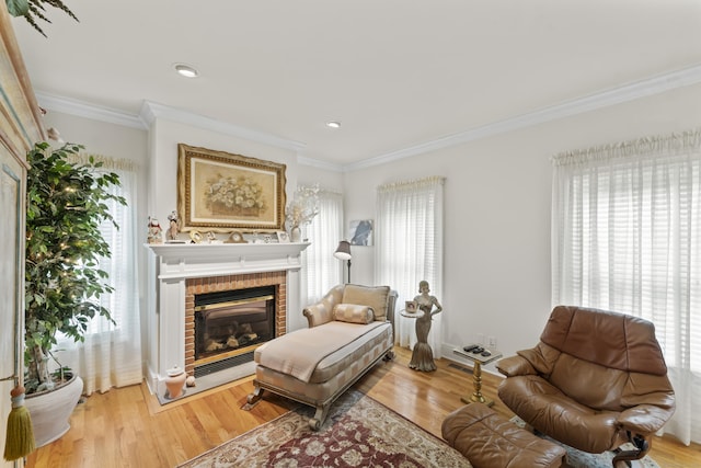 sitting room with light wood-style floors, a fireplace, and ornamental molding