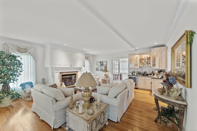 living area featuring beverage cooler, indoor wet bar, a fireplace, and crown molding