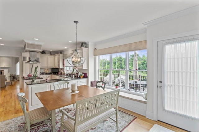 dining area featuring light wood-type flooring, an inviting chandelier, and crown molding