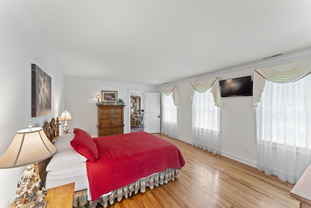 bedroom featuring ornamental molding, visible vents, baseboards, and wood finished floors