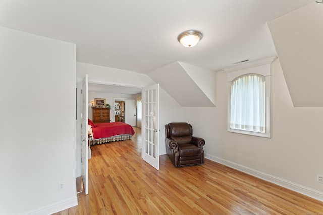 bedroom featuring lofted ceiling, visible vents, baseboards, french doors, and light wood-type flooring