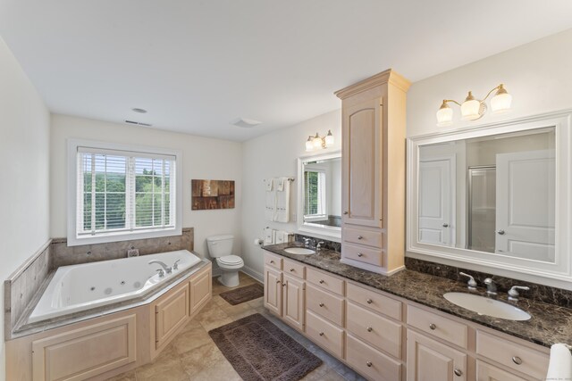 bathroom featuring double vanity, a tub with jets, a sink, and toilet