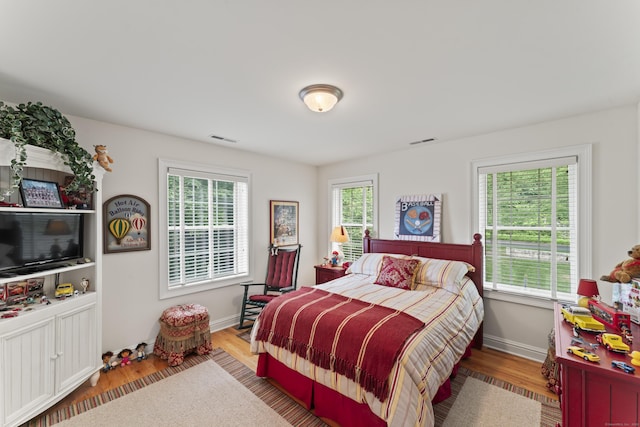 bedroom featuring multiple windows, visible vents, and wood finished floors