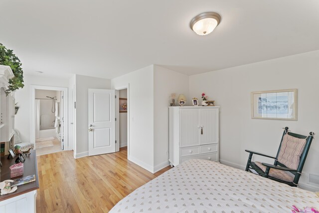 bedroom featuring ensuite bathroom, light wood finished floors, visible vents, and baseboards