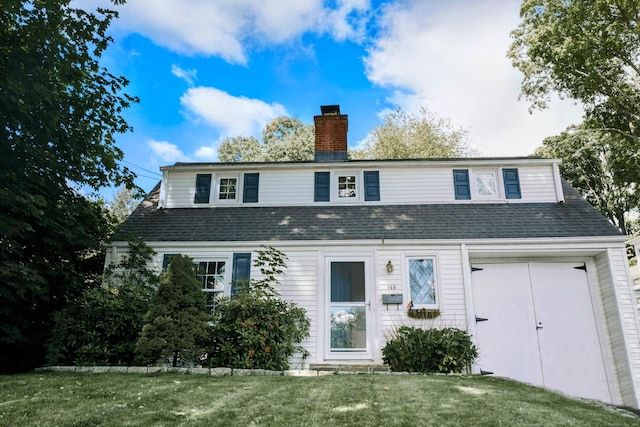 view of front facade with a front lawn, a chimney, and a shingled roof