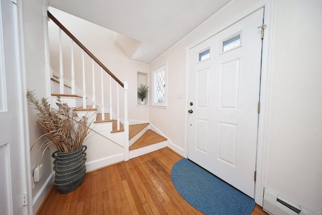 entryway with light wood-type flooring, a baseboard radiator, stairway, and baseboards