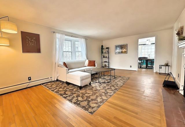 living area with a baseboard radiator, baseboards, and hardwood / wood-style floors