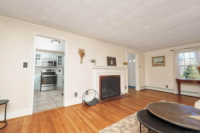 living room with baseboards, light wood-style flooring, baseboard heating, a textured ceiling, and a fireplace