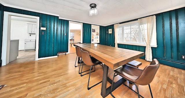 dining area with ornamental molding and light wood-style floors