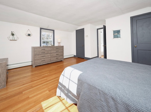 bedroom with a baseboard heating unit, lofted ceiling, and wood finished floors