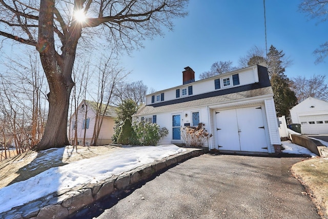 dutch colonial with an outbuilding, roof with shingles, aphalt driveway, and a chimney