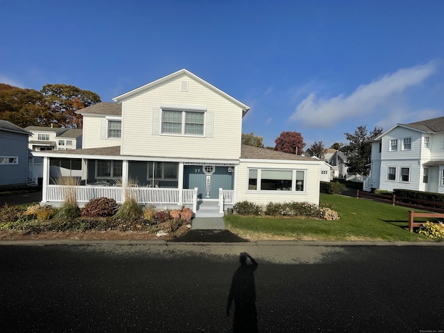 view of front of home with a sunroom, a porch, and a front lawn