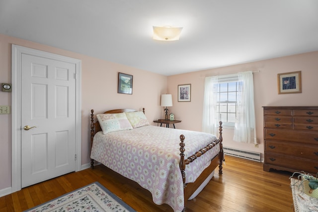 bedroom featuring baseboards, baseboard heating, and wood finished floors