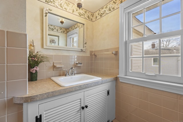 bathroom with a wainscoted wall, plenty of natural light, tile walls, and vanity