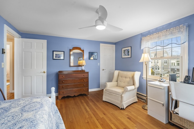 bedroom featuring light wood-type flooring, ceiling fan, baseboards, and baseboard heating