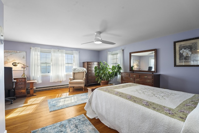 bedroom with a ceiling fan, baseboard heating, and wood finished floors