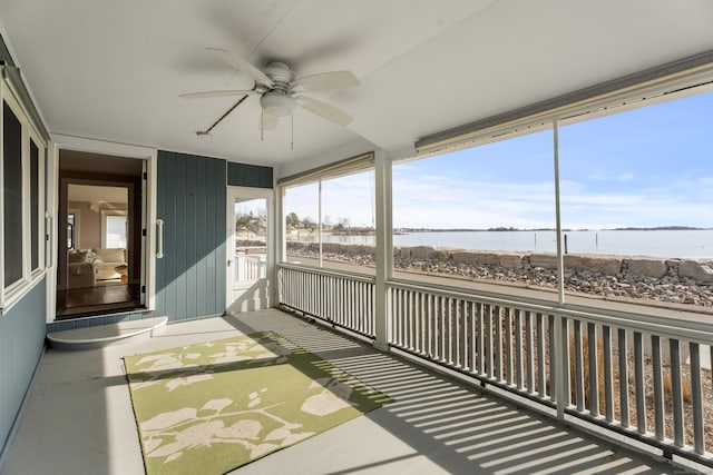 sunroom with a ceiling fan and a water view