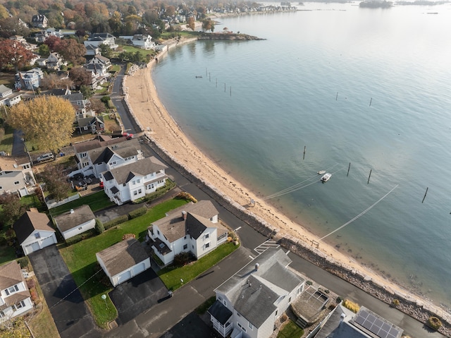 drone / aerial view featuring a water view, a residential view, and a beach view