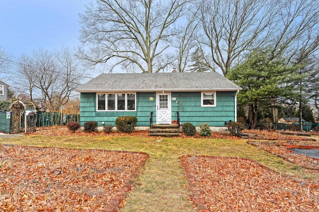 view of front of home featuring roof with shingles, a chimney, fence, and a front yard