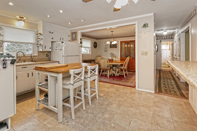 kitchen with a wealth of natural light, freestanding refrigerator, a sink, and backsplash