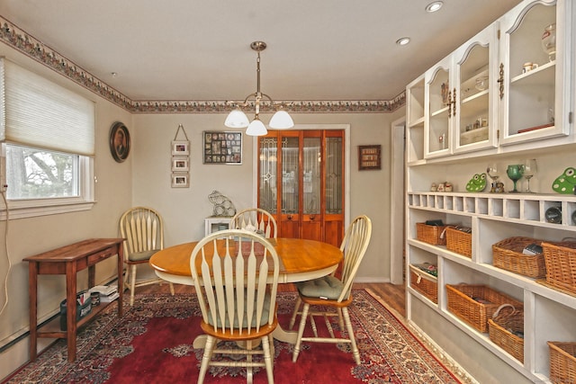 dining space with baseboards, a chandelier, and wood finished floors