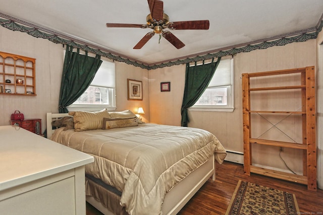 bedroom with ceiling fan, baseboard heating, and wood finished floors