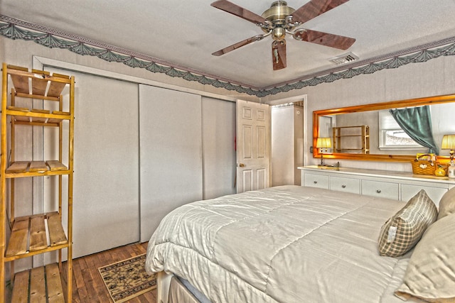 bedroom featuring a ceiling fan, a closet, visible vents, and dark wood finished floors