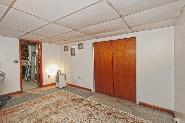 interior space with a closet, a drop ceiling, and baseboards