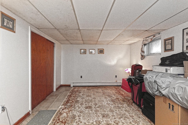 below grade area featuring a baseboard radiator, a paneled ceiling, and baseboards