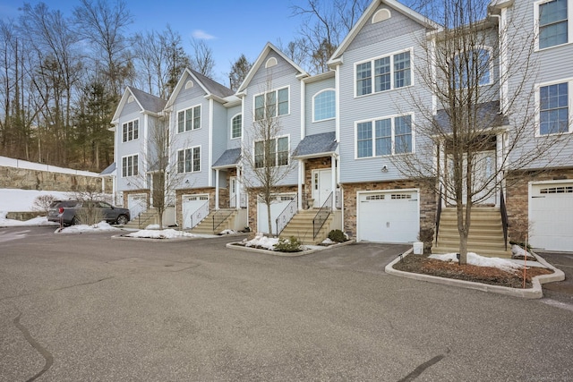 view of front of house with aphalt driveway, a residential view, stone siding, and an attached garage