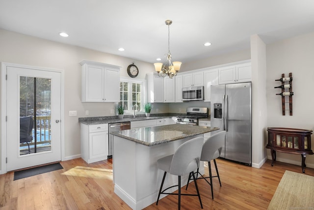 kitchen featuring appliances with stainless steel finishes, light wood-type flooring, white cabinetry, and a center island